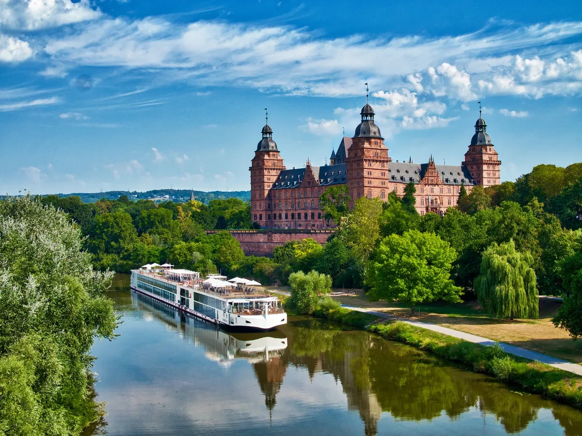 Viking river cruise ship passing a grand European castle on the river